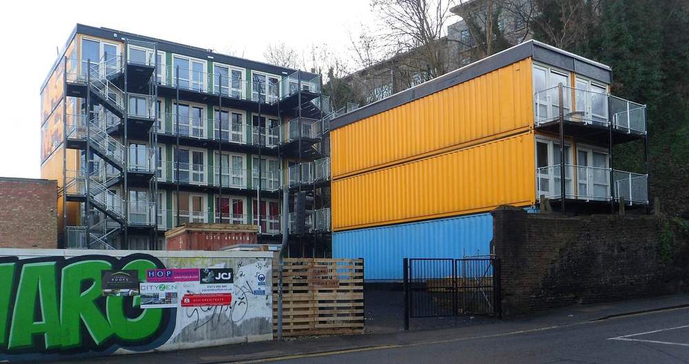 Shipping containers stacked into a multi-storey housing block with yellow and blue cladding